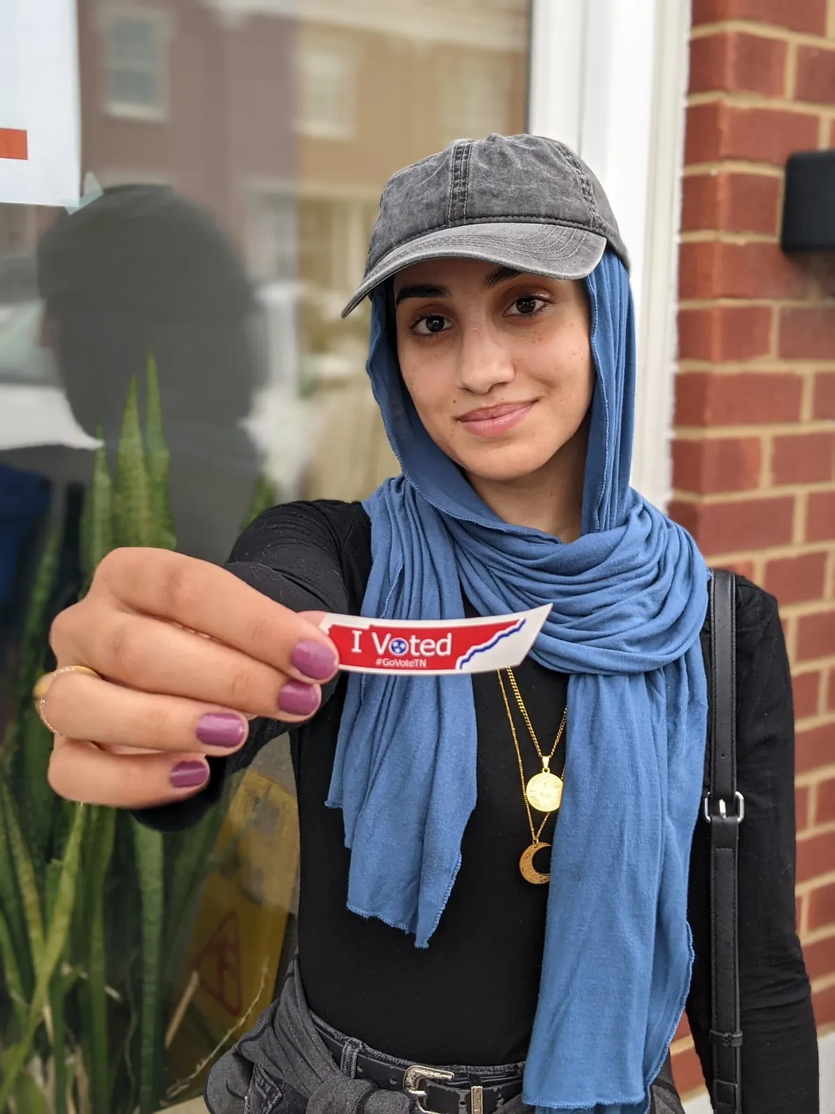 An MMY youth member holding an I Voted sticker at a civic engagement activity